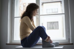 Sad young woman looking out of window