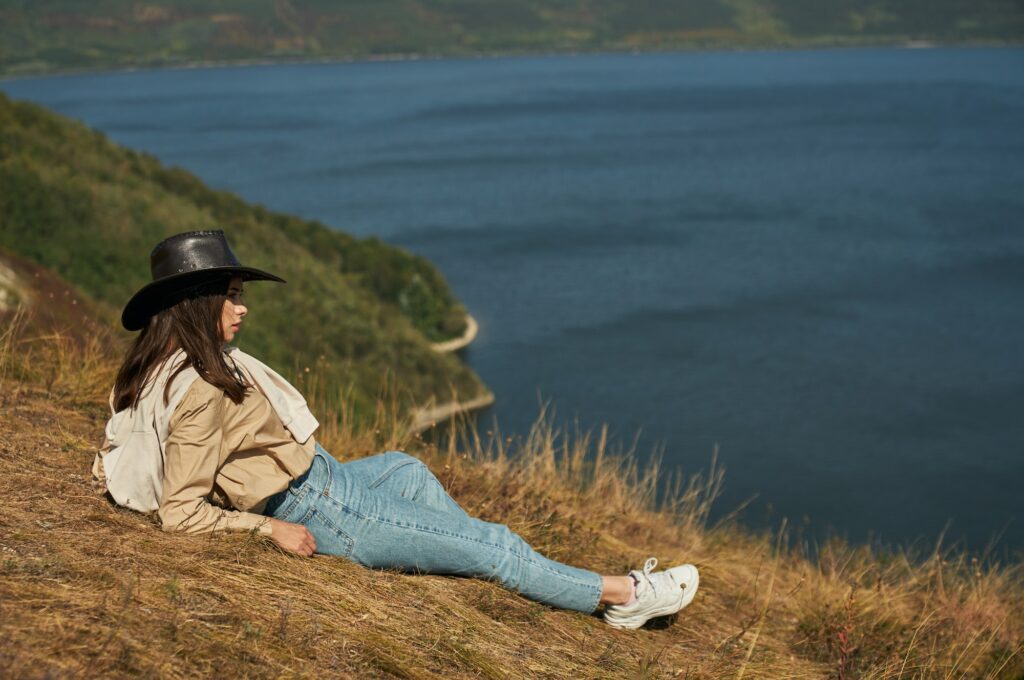 Woman lying on high hill and enjoying scenic landscape