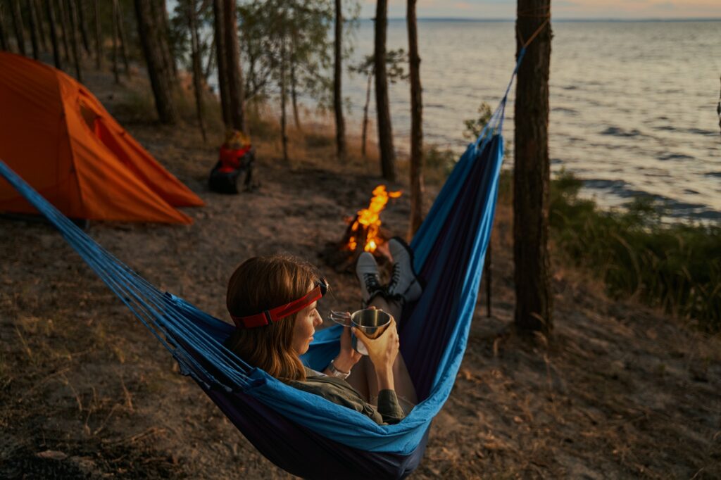 Pleased female traveller relaxing with drink in hammock
